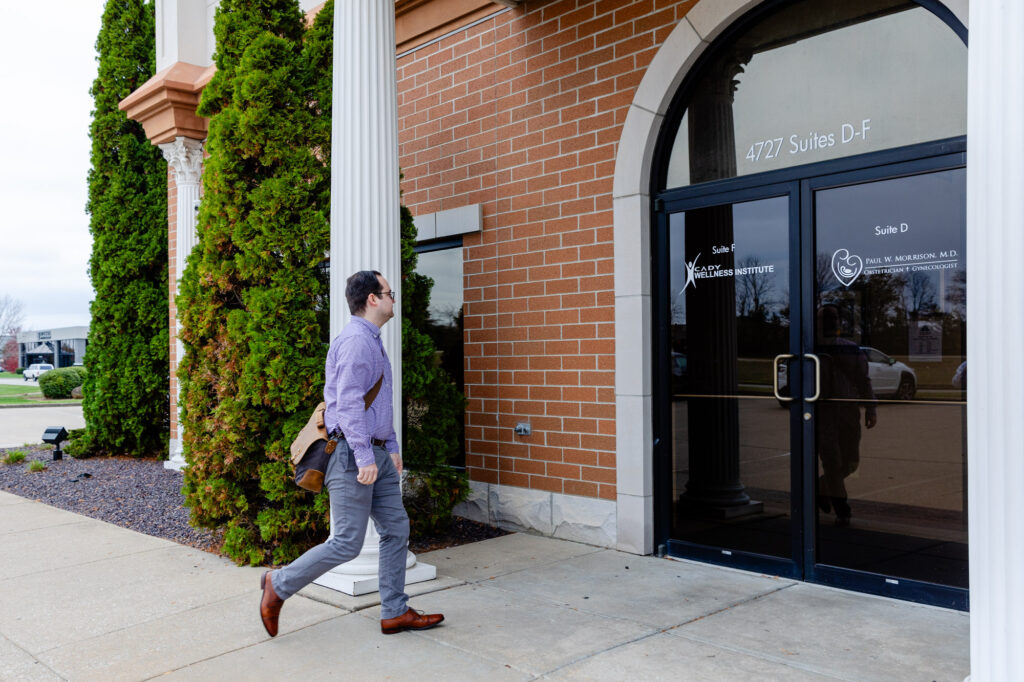 A well-dressed man approaching the front doors of a brick-faced building. The building is home to Cady Wellness Institute, a psychiatrist near Owensboro.